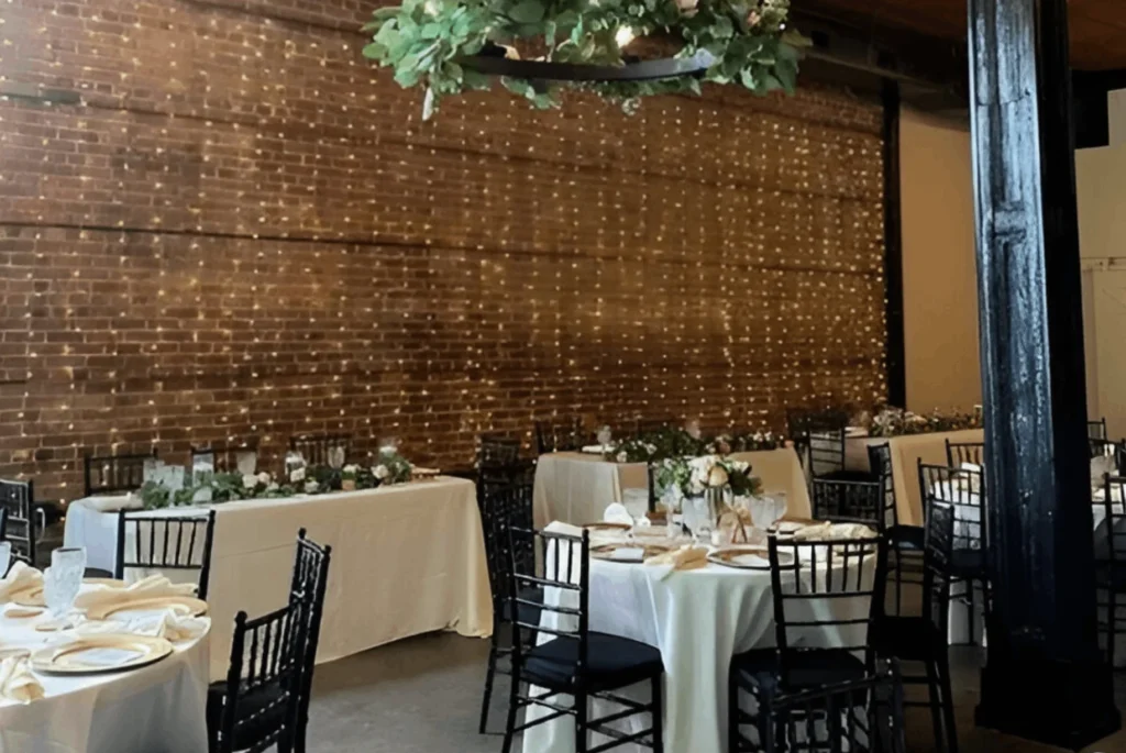 A room with tables and chairs, a chandelier and a wall.