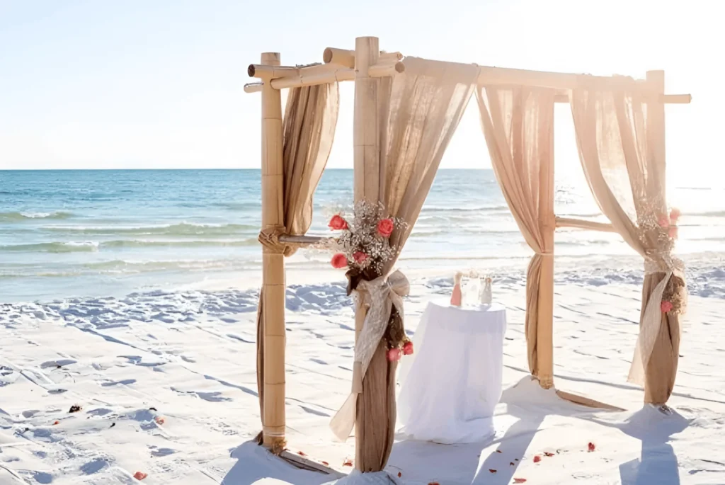 A wedding arch on the beach with flowers.