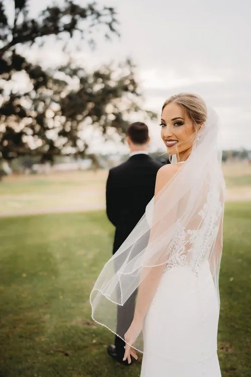 A bride and groom standing in the grass.