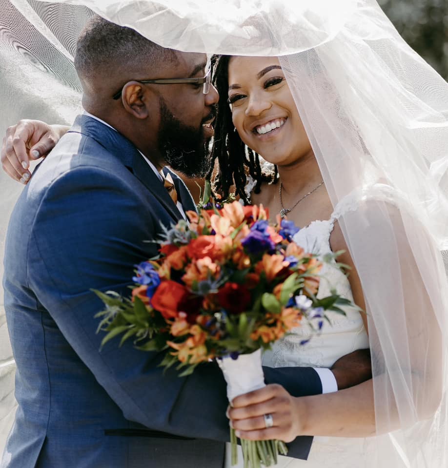 A man and woman kissing under the veil of a wedding.