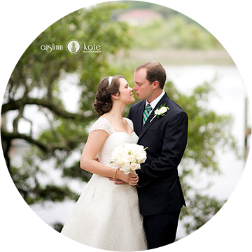 A bride and groom kissing in front of trees.