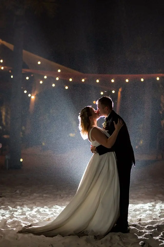 A bride and groom kissing in the dark.