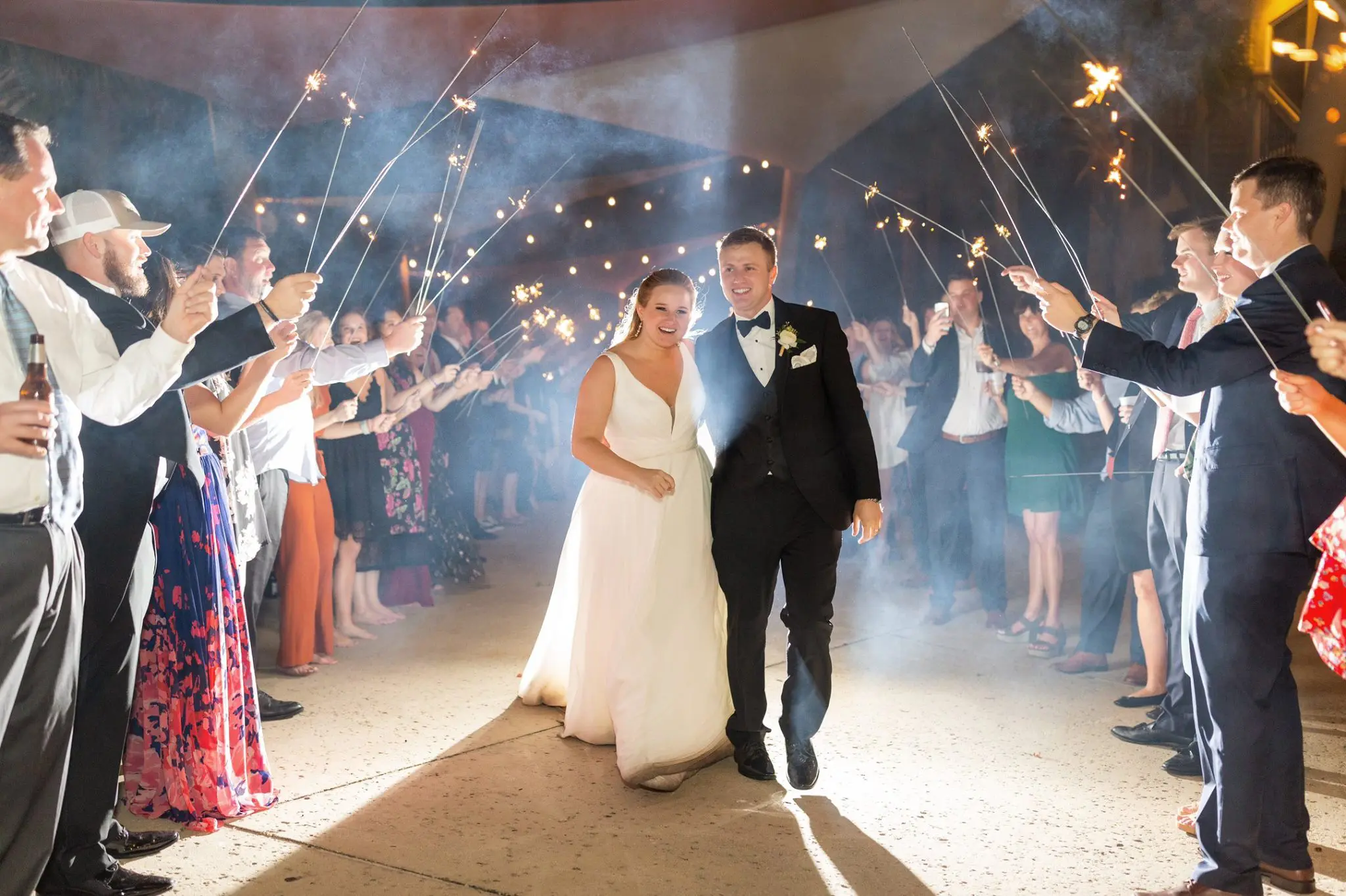 A bride and groom are walking through the sparklers.