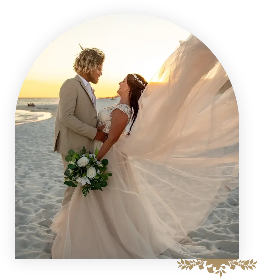 A bride and groom on the beach at sunset