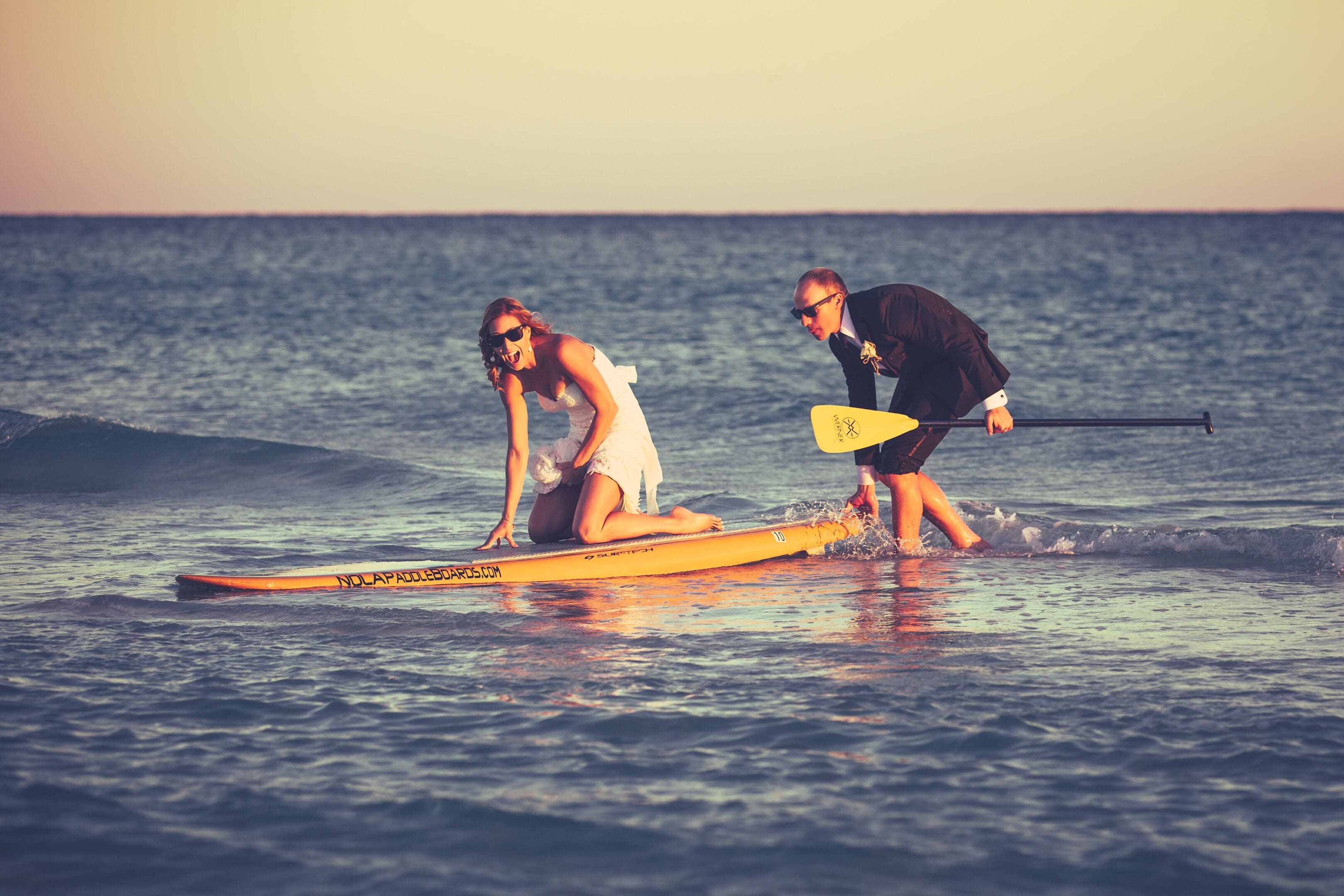 A man and woman on surfboards in the ocean.