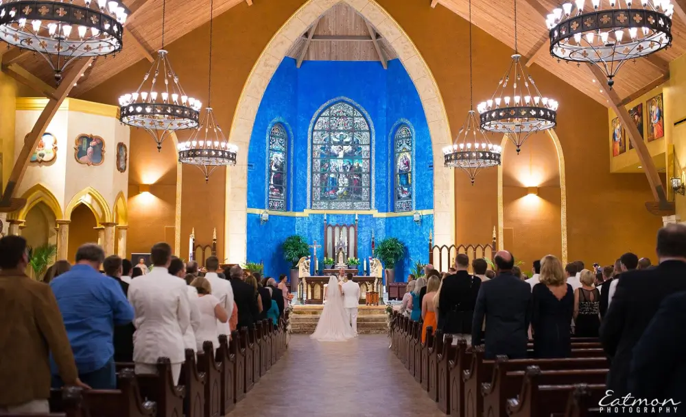 A church with people in the pews and stained glass windows.