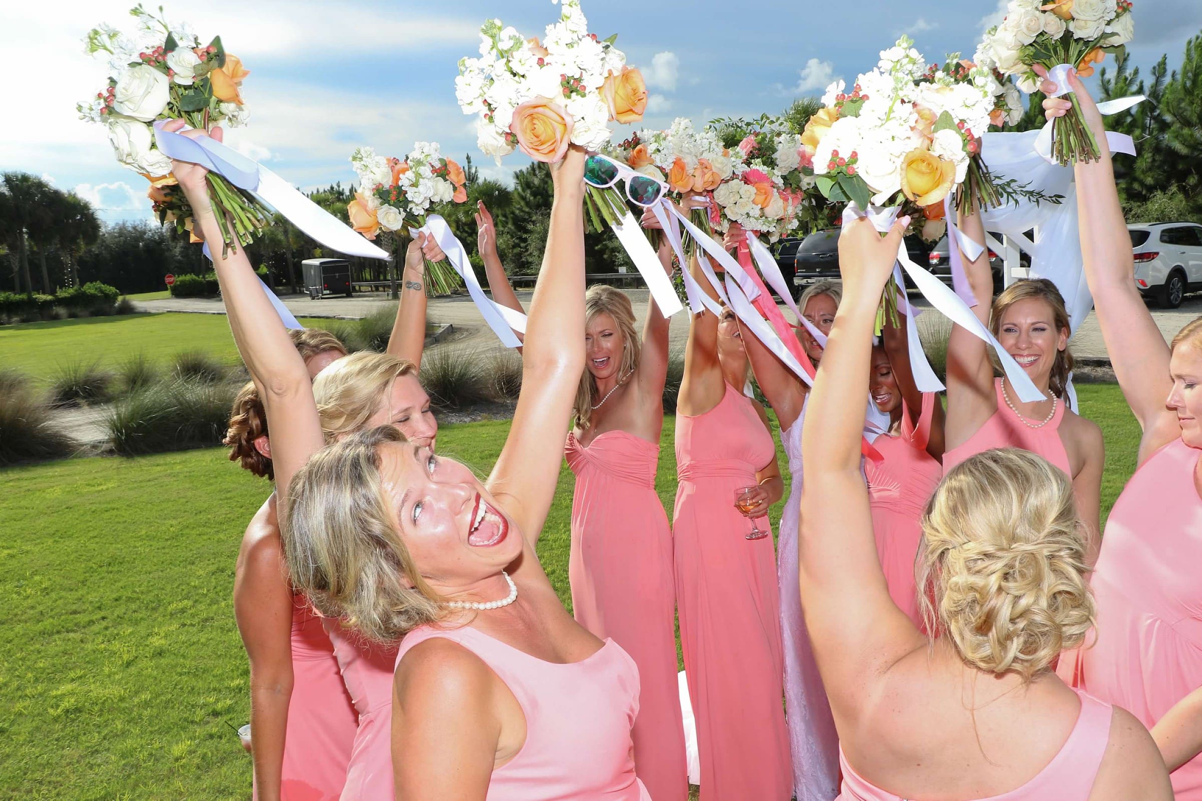 A group of women in pink dresses holding flowers.